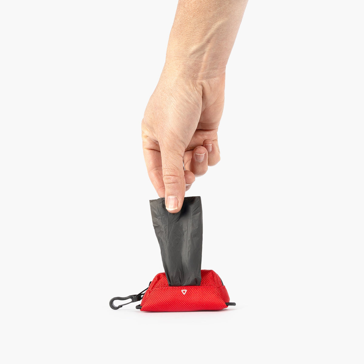 Hand pulling a black dog poop bad out of a red Essential Dog Poop Bag Holder